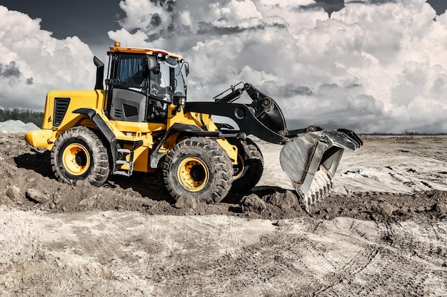 Krachtige bulldozer of lader verplaatst de aarde op de bouwplaats tegen de lucht Een grondverzetmachine egaliseert de site Bouw zwaar materieel voor grondwerken