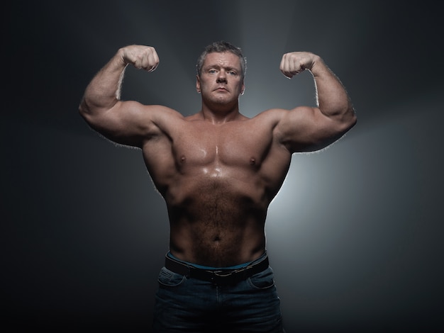 Krachtige gespierde bodybuilder poseren op zwart. concept sterkte en gezondheid