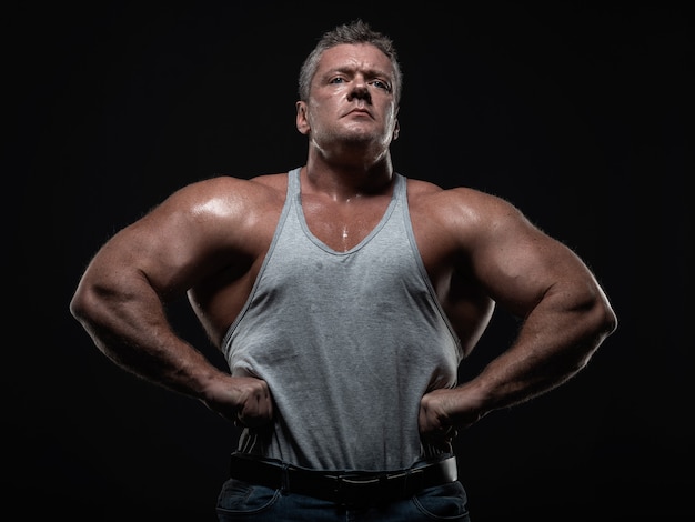 Krachtige gespierde bodybuilder poseren op zwart. concept sterkte en gezondheid