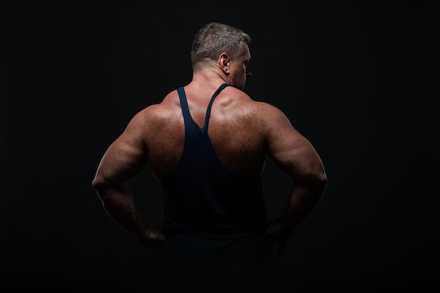 Krachtige gespierde bodybuilder poseren op zwart. concept sterkte en gezondheid