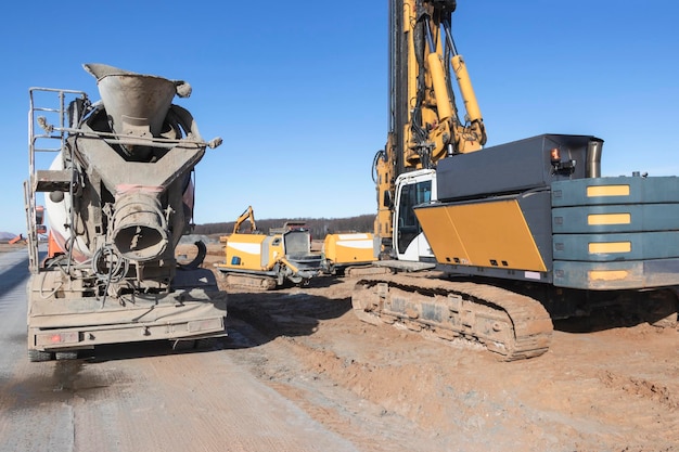 Krachtige hydraulische boorinstallatie op een bouwplaats en voertuigmixer voor betonlevering Het apparaat van paalfunderingen Geboorde palen zware bouwmachines