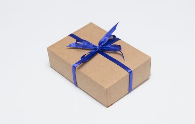 Kraft gift box with blue ribbon is on a white background.