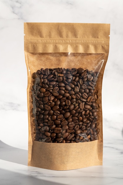 Photo a kraft paper bag with coffee beans for viewing with a highlighted shadow lies on a white background