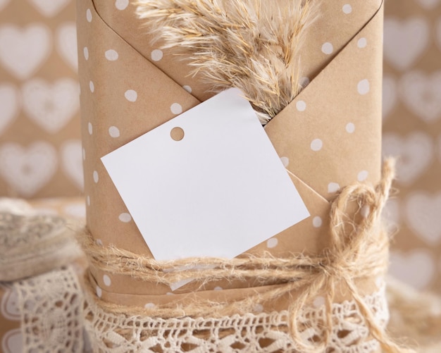 Photo kraft paper wrapped present with square gift tag and pampas grass close up summer scene with blank label rustic cottage chic or bohemian mockup copy space