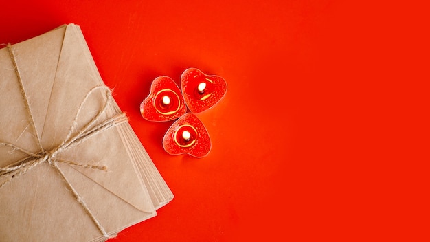 Kraftpapier-enveloppen met rode kaarsen op rood