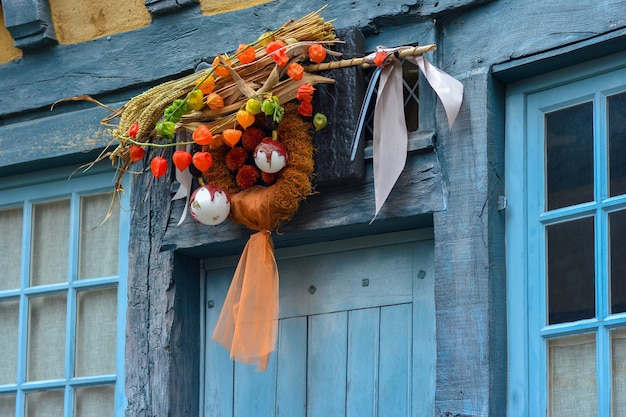 Krans van herfstplanten met physalis tarwe en kerstboom speelgoed op een blauwe deur