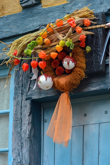 Krans van herfstplanten met physalis tarwe en kerstboom speelgoed op een blauwe deur