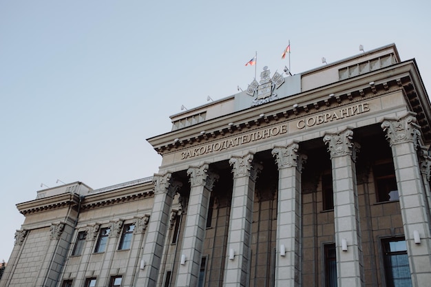 Krasnodar RUSSIA July 02 2022 The ancient building of the Legislative Assembly of Krasnodar Territory local government and laws Coat of arms waving flags of Kuban and the Russian Federation