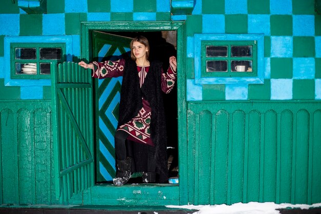 Krasnoilsk Oekraïne 13 jan 2017 een jong meisje tegen de achtergrond van een groenblauwe traditionele muur van een huis in een Oekraïens dorp