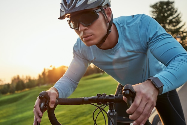 Krijg een snellere serieuze jonge mannelijke racer in sportkleding en een beschermende helm die er tijdens het rijden gefocust uitziet