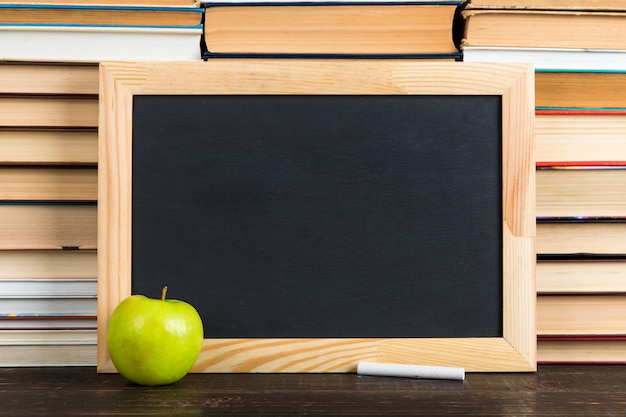 Krijtbord, appel en krijt, tegen boeken, exemplaarruimte.