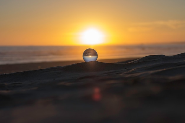 Kristalbol op het zand in een zonsondergang wordt neergestreken die