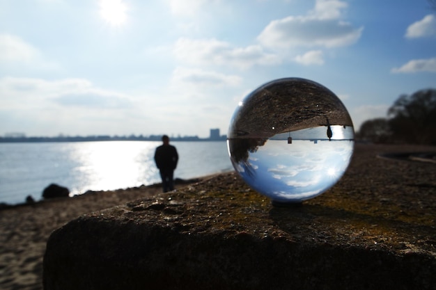 Foto kristallen bal op het strand door een man tegen de lucht