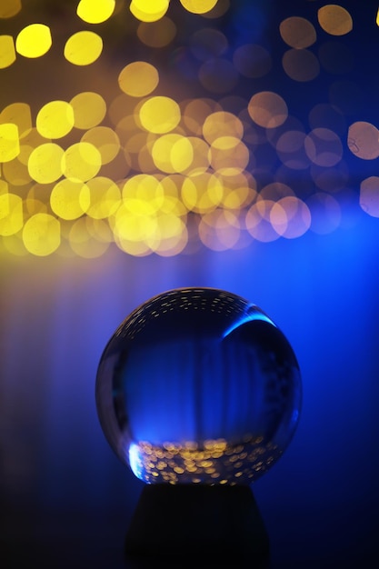 Foto kristallen bol op de vloer met bokeh, lichten erachter. glazen bol met kleurrijk bokehlicht, nieuwjaarsviering concept.