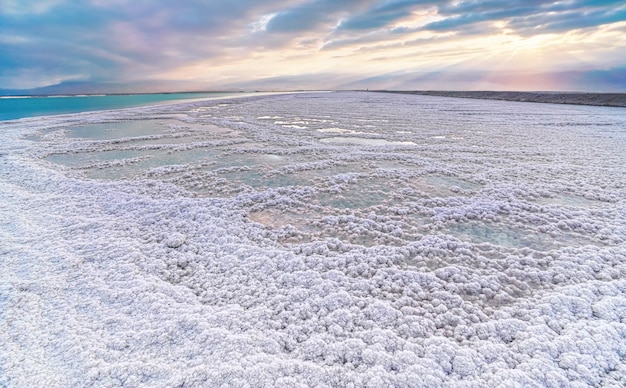 Kristallijn wit zout strand verlicht door ochtendzon, kleine poelen met zeewater aan de Dode Zee - 's werelds meest hypersaline meer