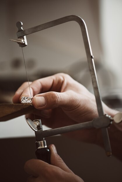 Kritieke momentclose-upfoto van juweliershanden die een zilveren ring maken met professionele verstelbare