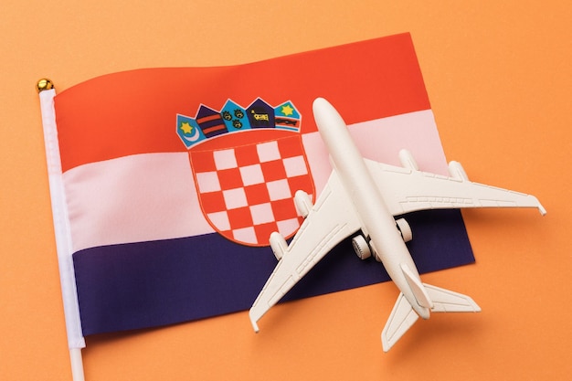 Kroatische vlag en speelgoedvliegtuig op gekleurde achtergrond, concept rond het thema reizen naar Kroatië