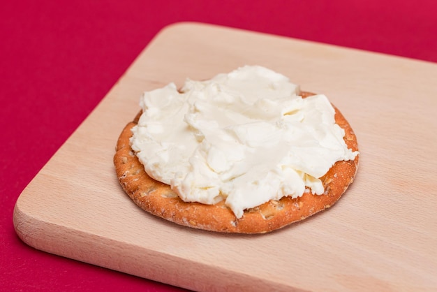 Krokant broodje cracker met roomkaas op houten plank