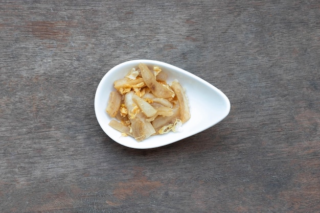 Krokant gebakken pok en knoflook in witte keramische beker op houten tafel Thais eten