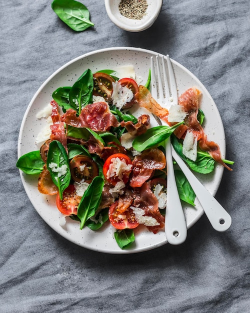 Krokant gebakken prosciutto cherry tomaten spinazie Parmezaanse kaas salade op grijze achtergrond