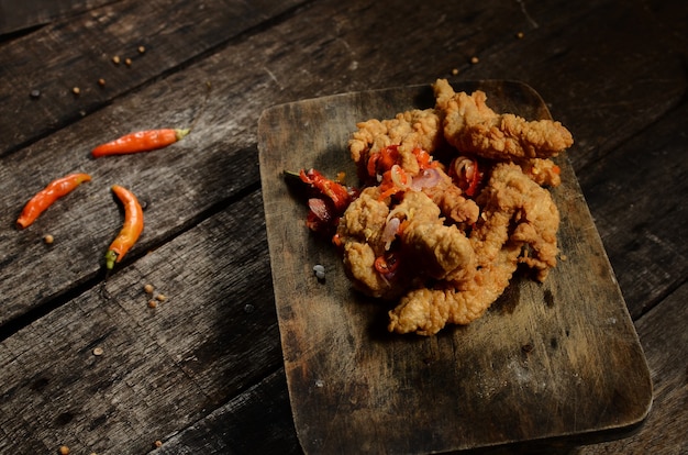 Krokant gebakken stukjes kipfilet en Balinese sambal matah op een houten tafel