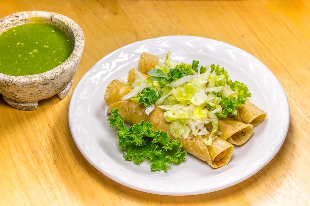 Foto krokant gebakken taco's op een witte schotel met de groene saus