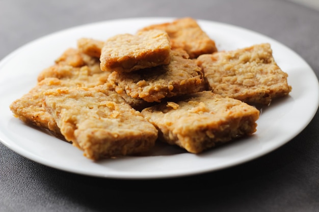 Krokant gebakken tempeh op een wit bord met een grijze achtergrond