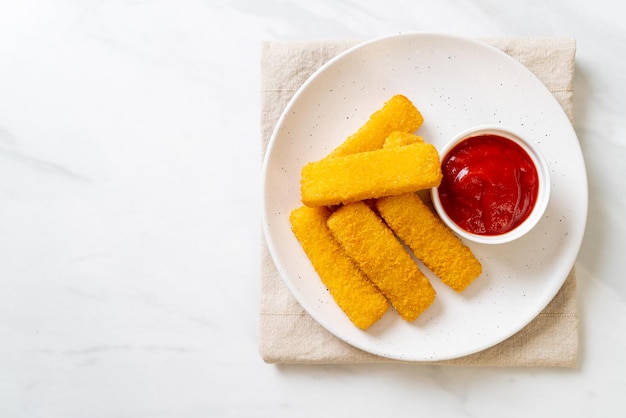 Krokant gebakken vissticks met paneermeel geserveerd op bord met ketchup