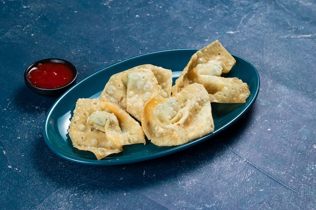 Krokant gebakken wonthon dim sum wraps met tomatensaus geserveerd in een gerecht geïsoleerd op tafelblad