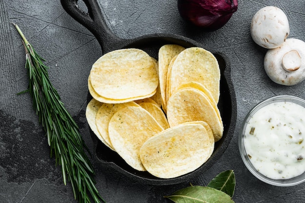 Krokante aardappelchips met dipsauzen op grijze stenen achtergrond bovenaanzicht plat gelegd