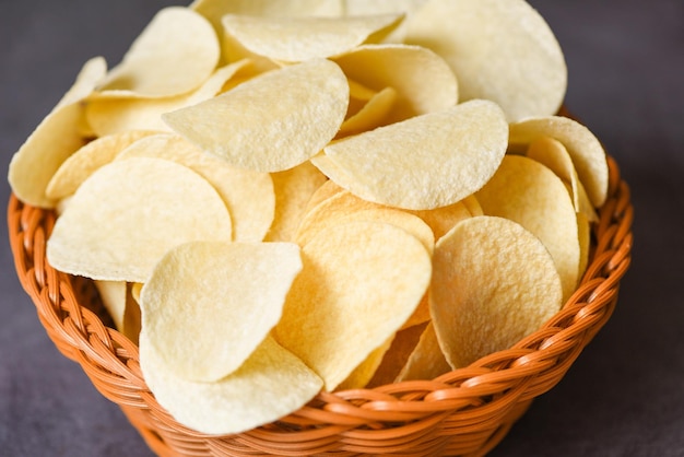 Krokante aardappelchips op de voedseltafel zwarte achtergrond Aardappelchips snack op mand