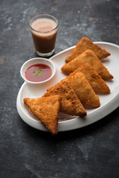 Krokante Aardappeldriehoeken of batata vada bedekt met paneermeel en daarna gefrituurd. geserveerd met tomatenketchup. selectieve focus