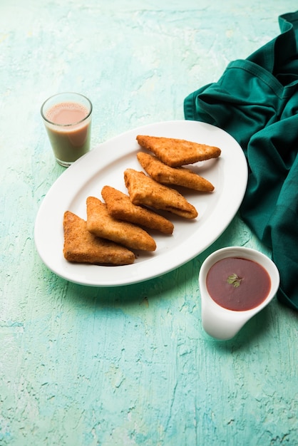 Krokante Aardappeldriehoeken of batata vada bedekt met paneermeel en daarna gefrituurd. geserveerd met tomatenketchup. selectieve focus