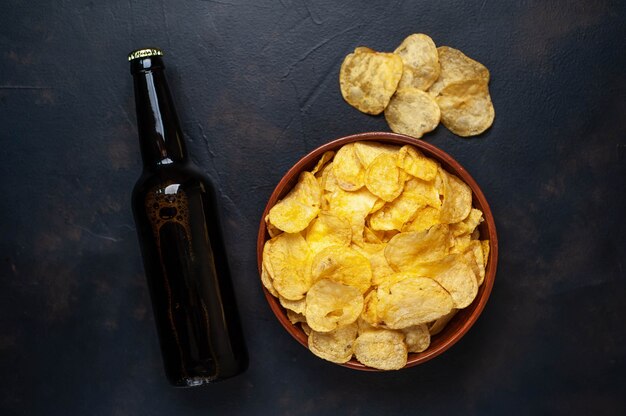 Krokante chips in een kom en bier op een stenen achtergrond