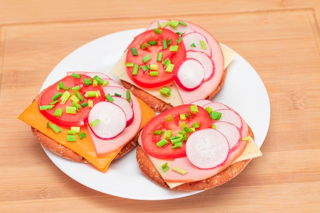 Krokante crackersandwiches met tomatenworst, kaas, groene uien en radijs