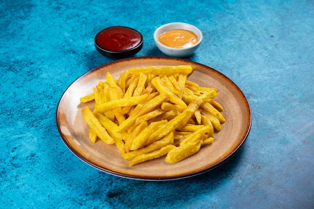 Krokante frietjes of chips met mayo dip en tomatensaus geserveerd in een bord zijaanzicht