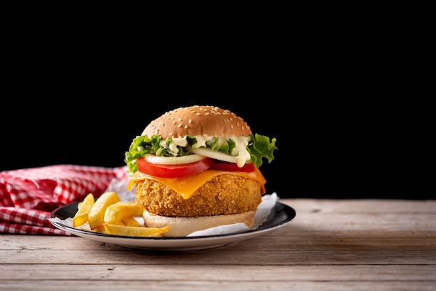 Krokante kipburger met kaas en frietjes op houten tafel