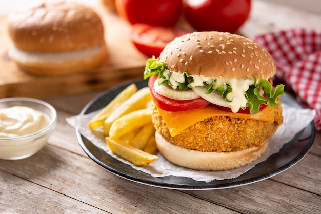 Krokante kipburger met kaas en frietjes op houten tafel