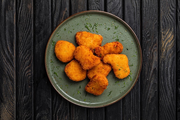 Krokante kipnuggets op een bord op een donkere houten achtergrond