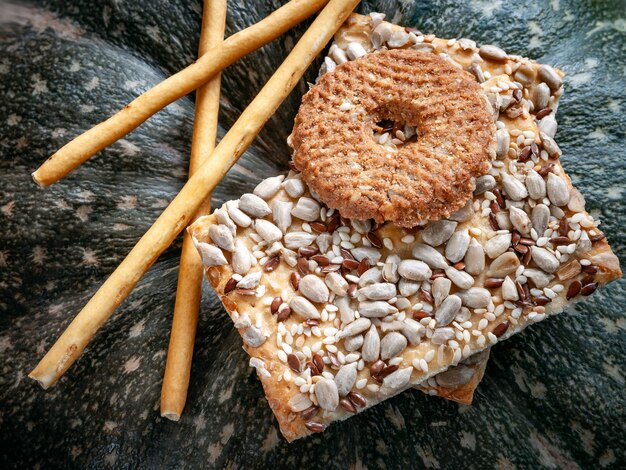 Krokante koekjescrackers met vlaszonnepitten en sesam tegen een donkere pompoenachtergrond