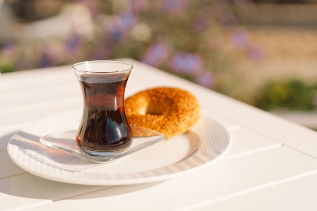 Krokante Turkse traditionele bagel simit met sesam en glas Turkse zwarte thee