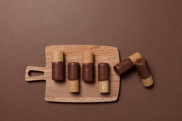 Krokante wafelrolletjes half omhuld met melkchocolade op serveerplank
