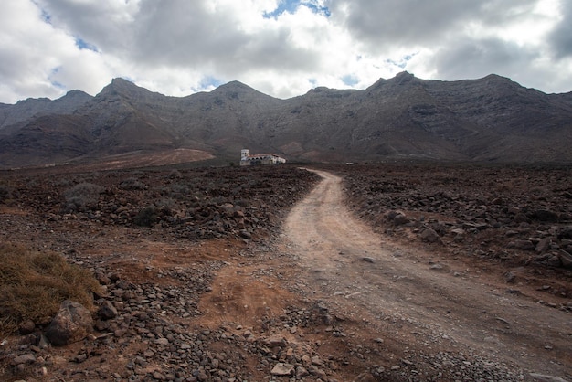 kronkelende weg die leidt naar een mysterieus huis onder de bergen van Cofete, Fuerteventura