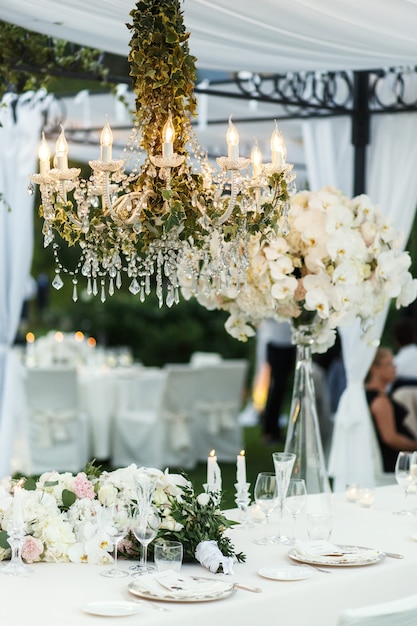 Foto kroonluchter met bloemen en groen hangt over de eettafel voor pasgetrouwden