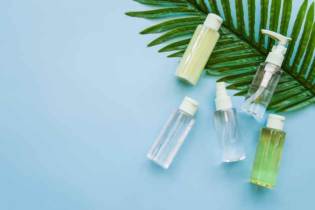 Kruiden cosmetische productfles op groen blad tegen blauwe achtergrond