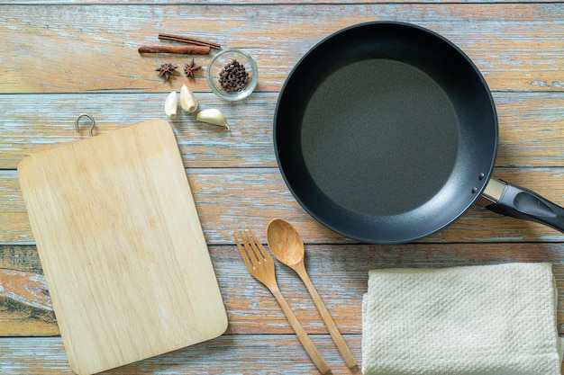 Kruiden en specerijen rond gietijzeren koekenpan op houten achtergrond Koken concept