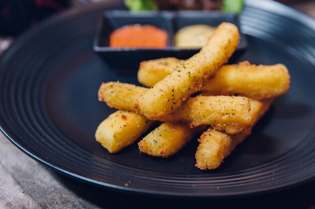 Kruidenfrieten geserveerd met mayonaise en duizend eilandsaus in zwarte plaat.