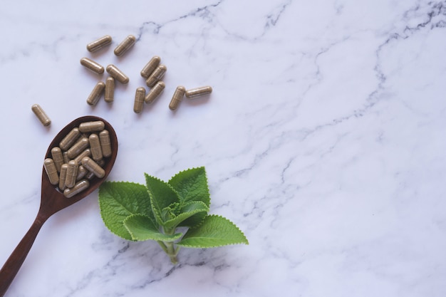 Kruidengeneeskunde in capsules op houten lepel