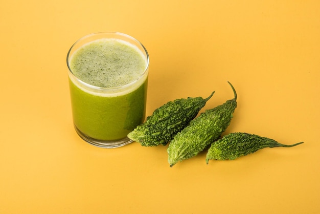 Kruidensap van Bittere kalebas of Karela is het beste natuurlijke medicijn voor diabetes. Hele bittere meloenen en glas vol sap bewaard over kleurrijke of houten achtergrond. Selectieve focus