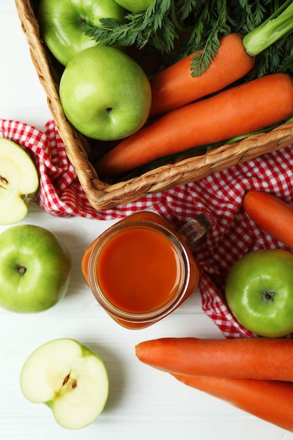 Kruik appel - wortelsap en ingrediënten op witte houten